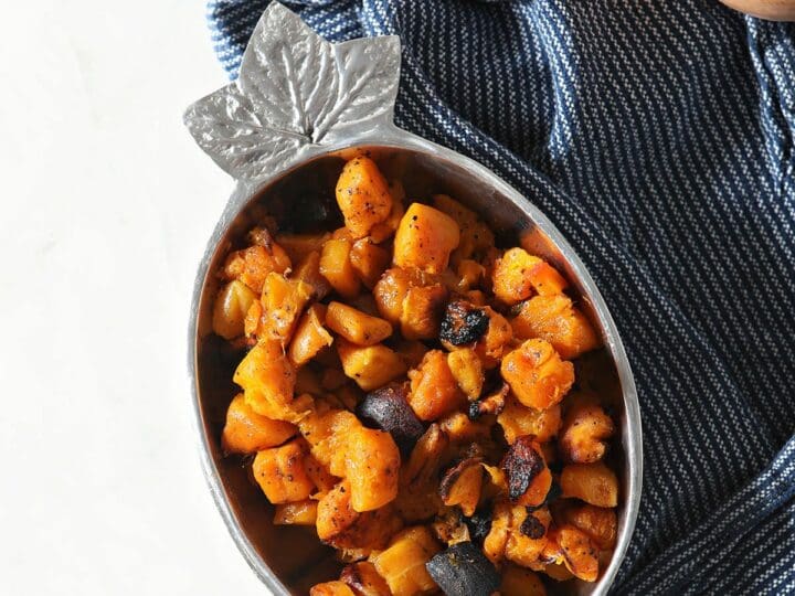 A bowl of roasted butternut squash on a blue towel