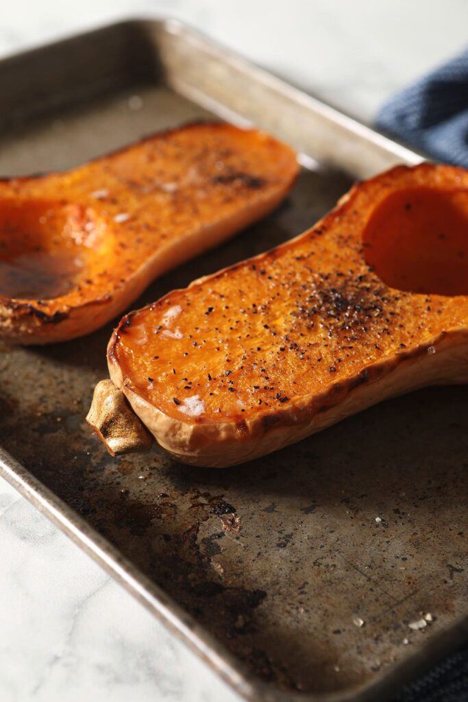 A sheet pan holding a halved roasted butternut squash