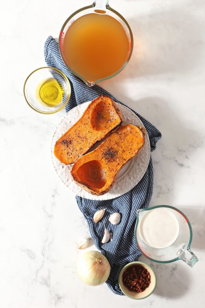 Roasted butternut squash on a plate with other ingredients for soup