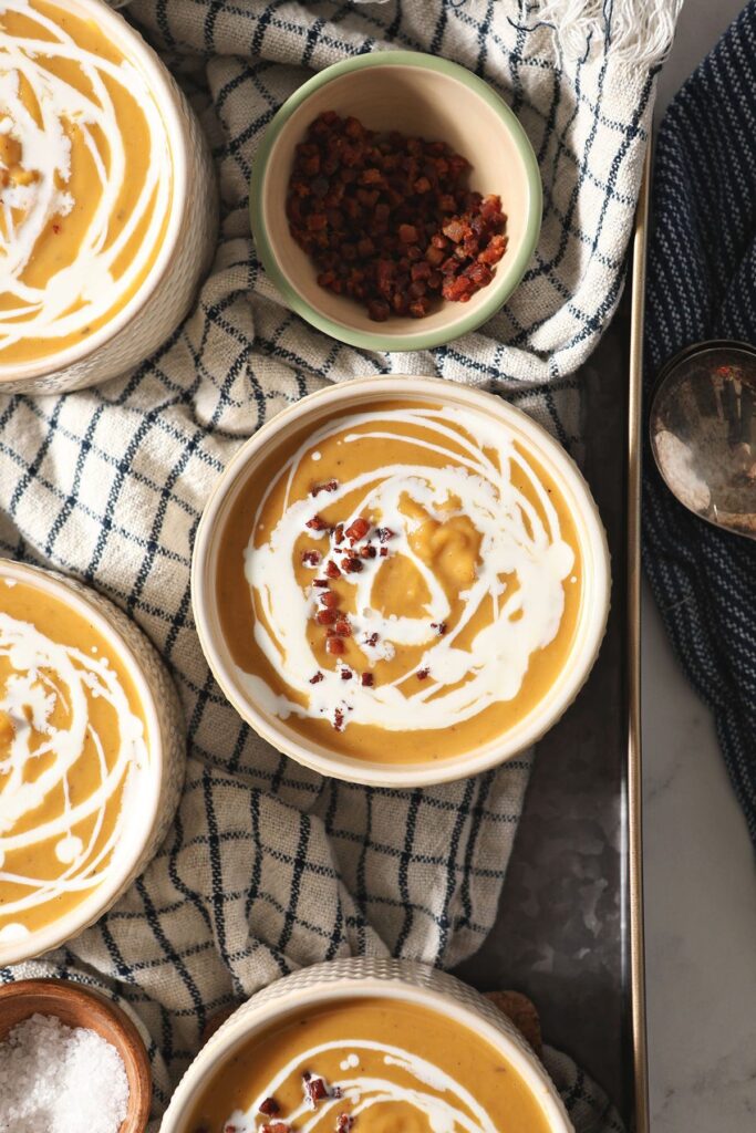 Four bowls of Roasted Butternut Squash Soup on a blue striped towel