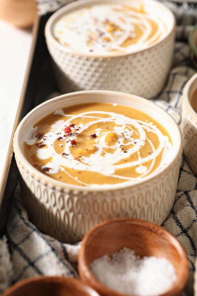 Close up of a bowl of Roasted Butternut Squash Soup swirled with cream and pancetta