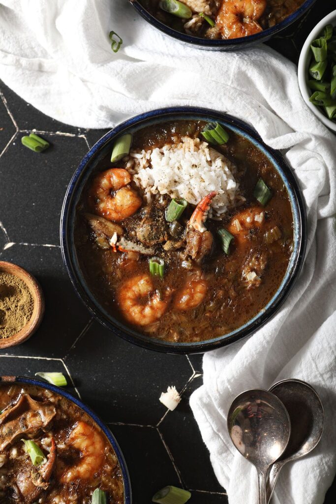 Three bowls of seafood gumbo with shrimp and crab from above