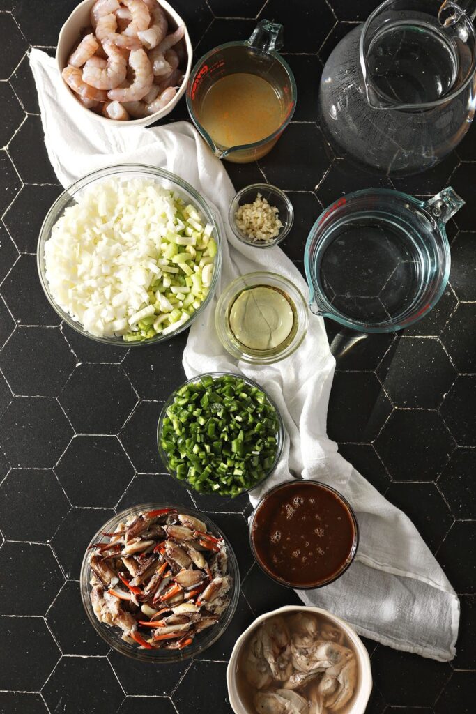 Ingredients for gumbo in bowls on black marble