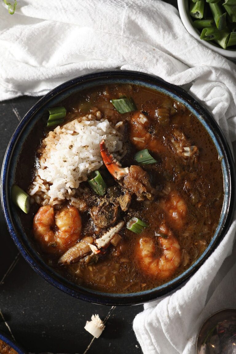 A bowl of seafood gumbo garnished with rice and green onions