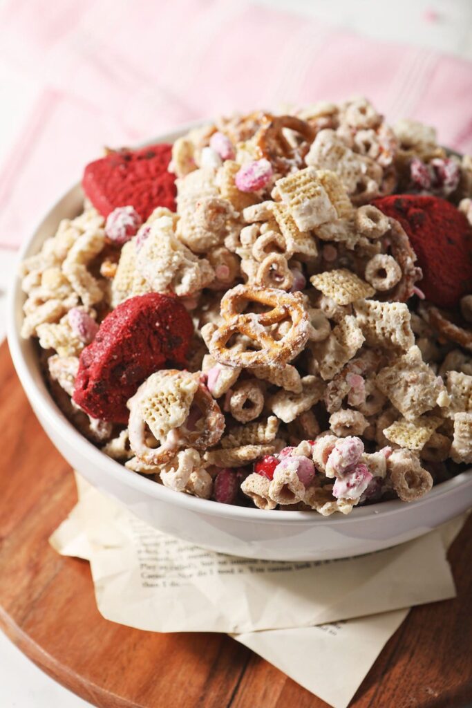 Close up of a bowl of Valentine's Day White Chocolate Chex Mix on wood