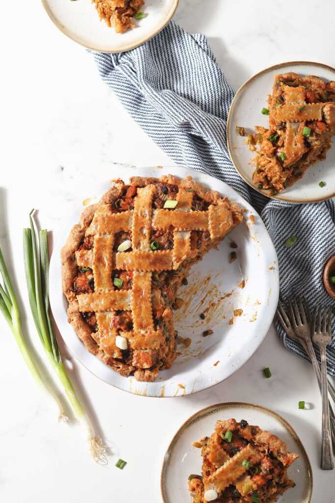 A sliced Crawfish Pie surrounded by plates with slices of pie