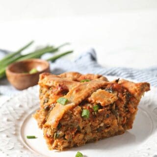 A slice of crawfish pie on a white plate by a blue striped towel