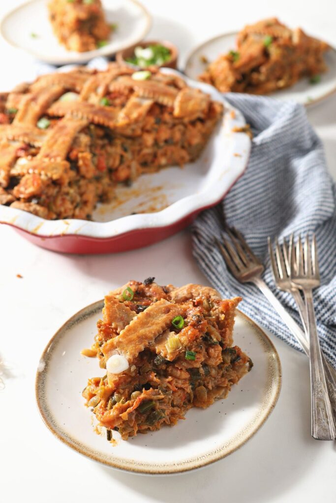 A slice of crawfish pie next to a pie plate with half a pie and forks