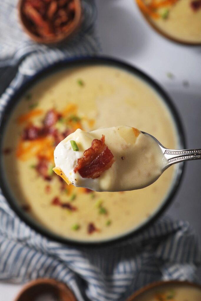 A spoonful of Baked Potato Soup over a bowl