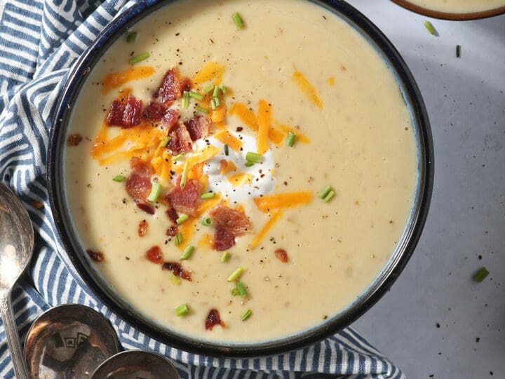 Three bowls of Slow Cooker Potato Soup garnished with bacon, cheese, sour cream and chives