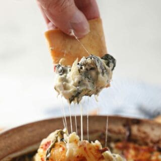 A pita chip scoops up hot Spinach Artichoke Dip