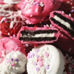 Red, white and pink Oreos stacked on a baking sheet