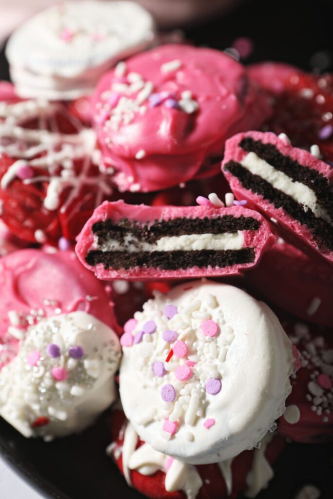 Red, white and pink Oreos stacked on a baking sheet