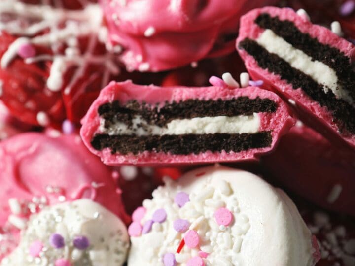 Red, white and pink Oreos stacked on a baking sheet