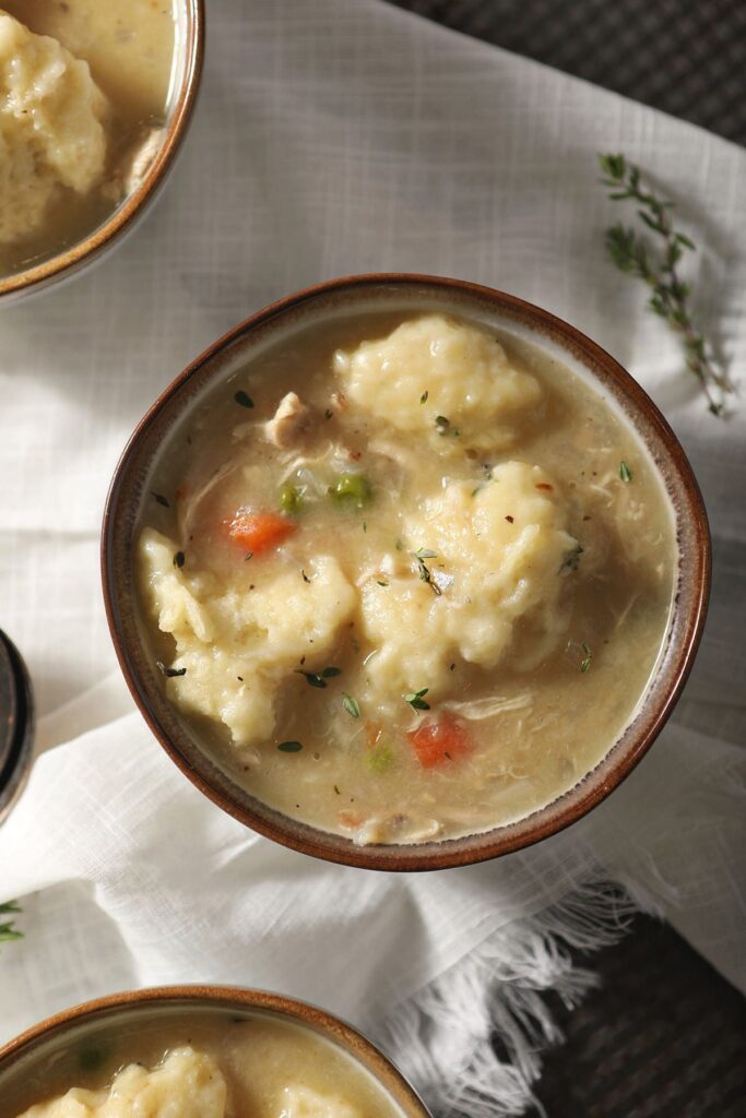 Close up of a bowl of Dutch Oven Chicken and Dumplings on a linen cloth