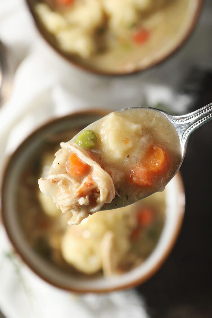 A spoonful of Chicken and Dumplings over a bowl