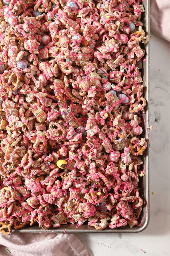 Bunny Bait snack mix in a baking sheet after being drizzled with pink candy melts