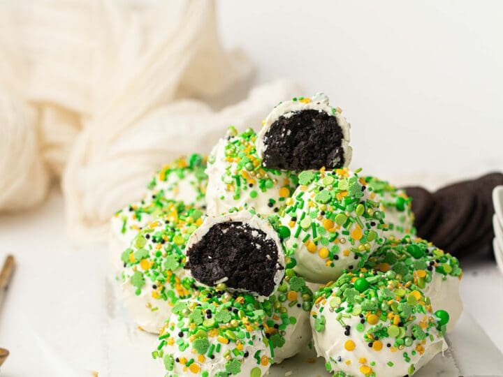 Green and white St. Patrick's Day oreo truffles on a white wooden board