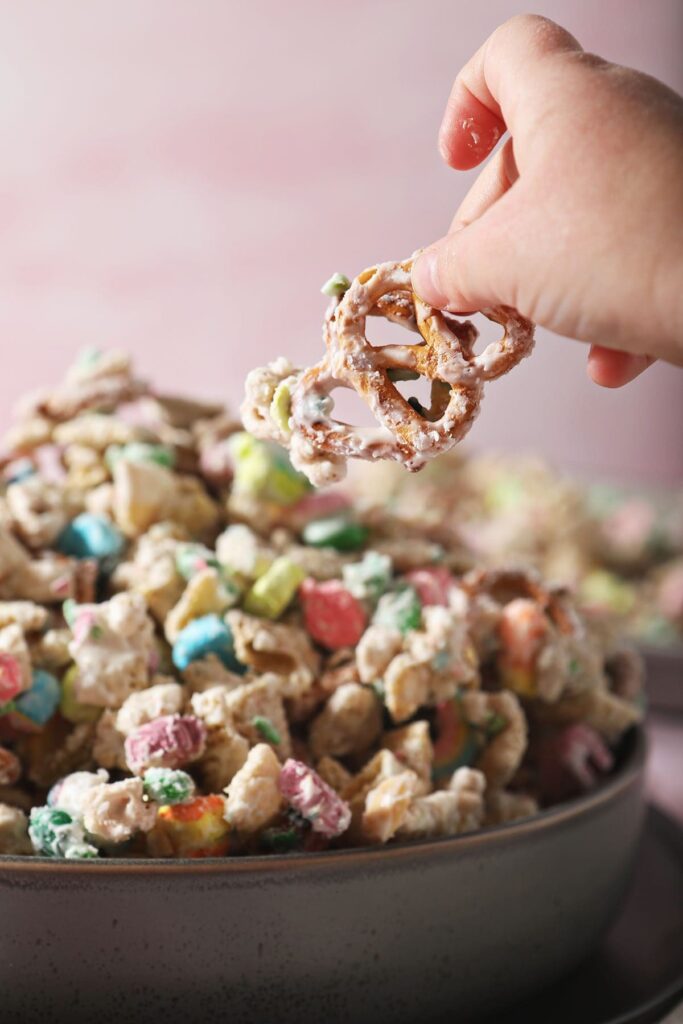 A child lifts a pretzel out of a bowl of snack mix for St. Patrick's Day