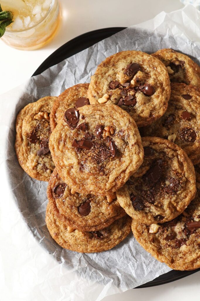 A plate of Browned Butter Chocolate Chip Cookies with Walnuts and Bourbon stacked on top of each other