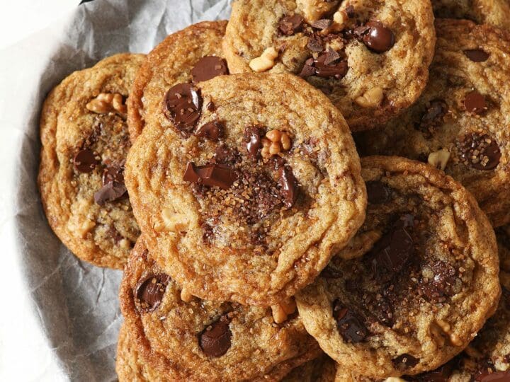 A plate of Browned Butter Chocolate Chip Cookies with Walnuts and Bourbon stacked on top of each other
