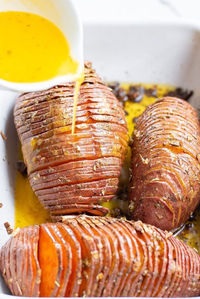 A butter-parmesan sauce is drizzled onto a baked sweet potato