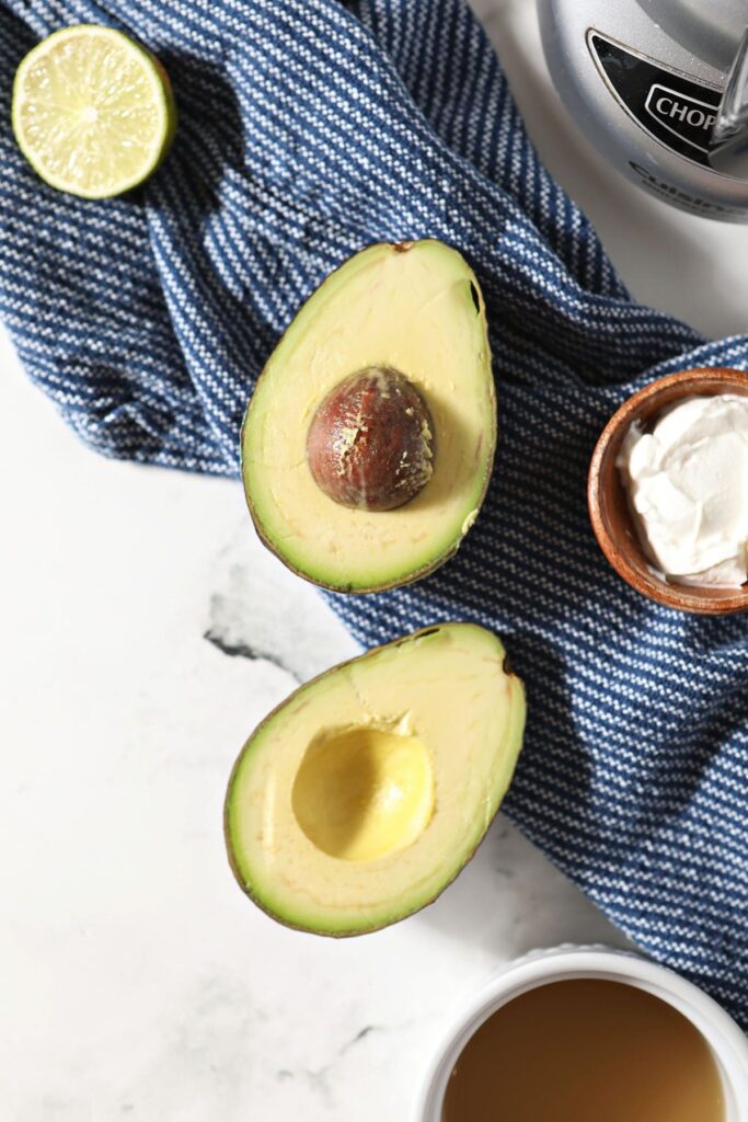 An avocado with lime and sour cream on a blue towel