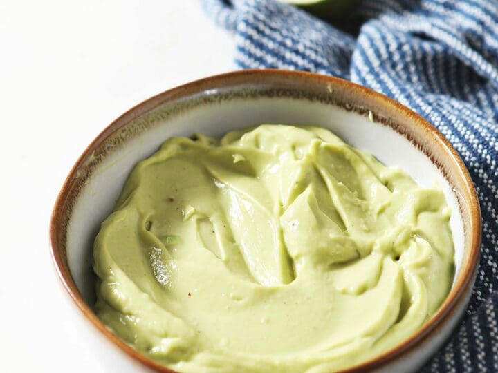 A bowl of Avocado Cream Sauce on marble with a blue towel