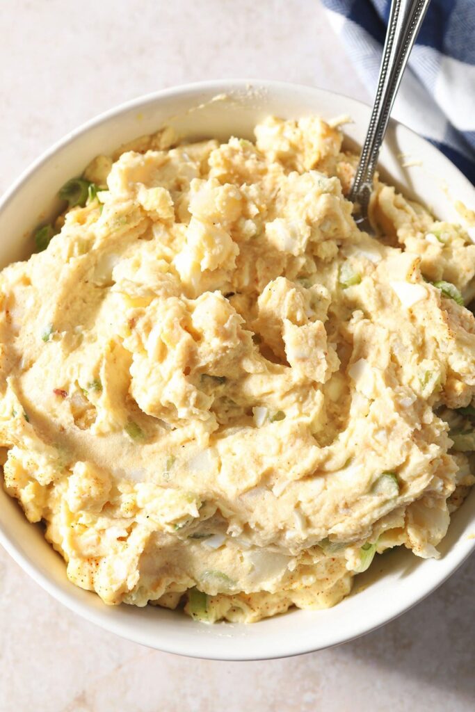 Close up of creamy potato salad in a bowl with a spoon