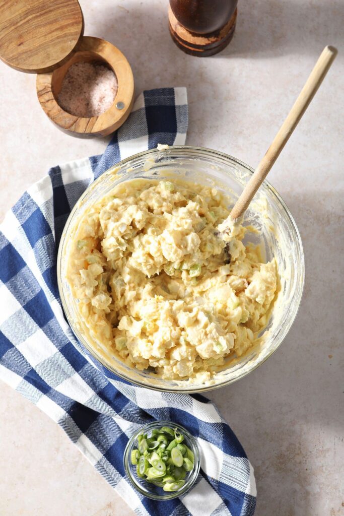 Potato salad in a bowl with a wooden spoon after mixing