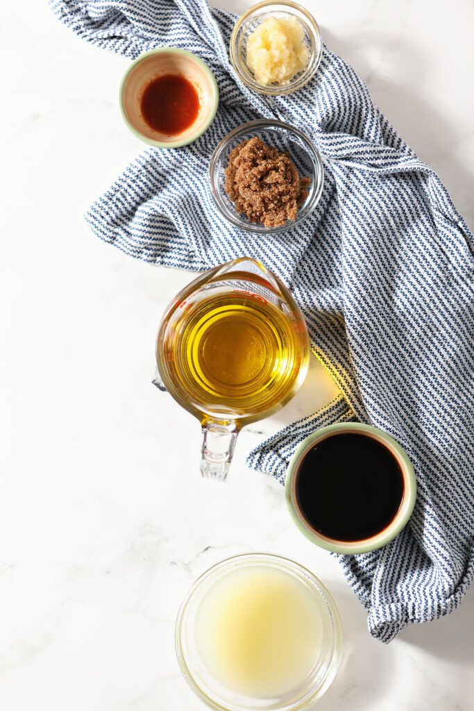 Ingredients to make steak marinade in bowls on a marble with a blue towel