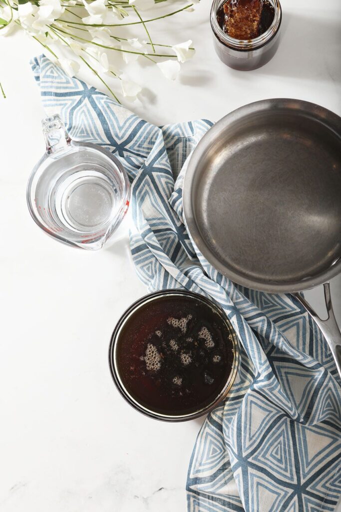 Honey and water with a saucepan, flowers and a blue geometric towel on marble