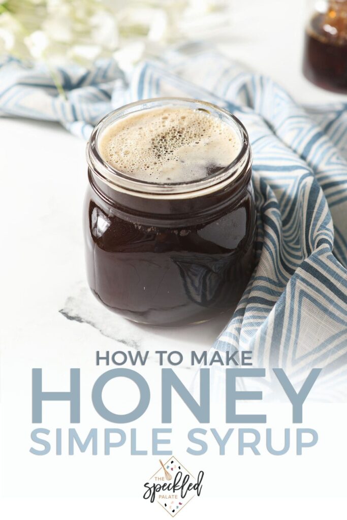 A jar of honey syrup on marble next to a geometric blue towel and flowers with the text how to make honey simple syrup