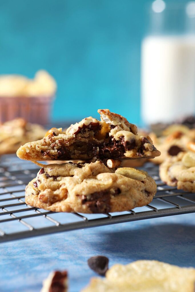 A half-eaten cookie sits on top of another cookie on a metal cooling rack