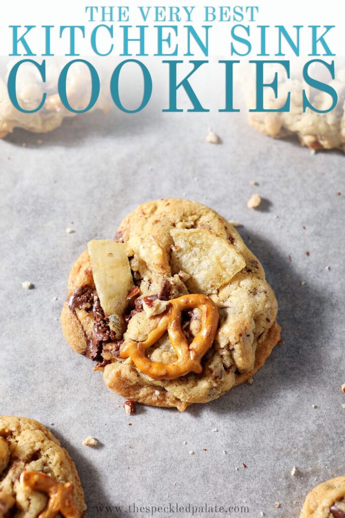 A just-baked kitchen sink cookie on a sheet pan with the text the very best kitchen sink cookies