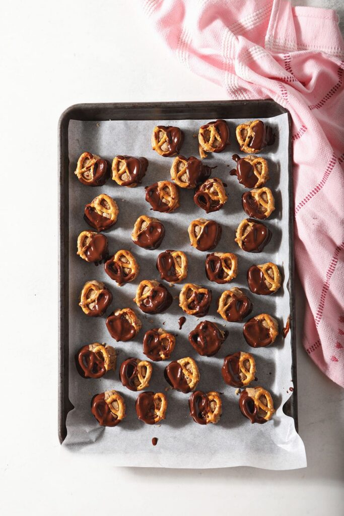 Chilled Peanut Butter Pretzel Bites dipped in chocolate on a baking sheet