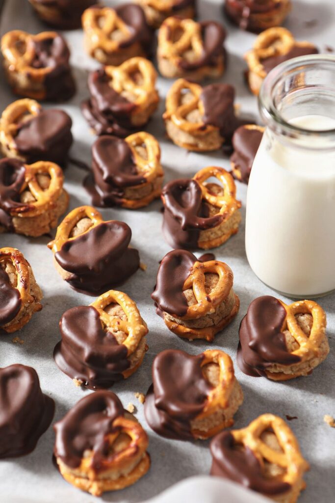 Several Peanut Butter Pretzel Bites next to a glass of milk on a baking sheet