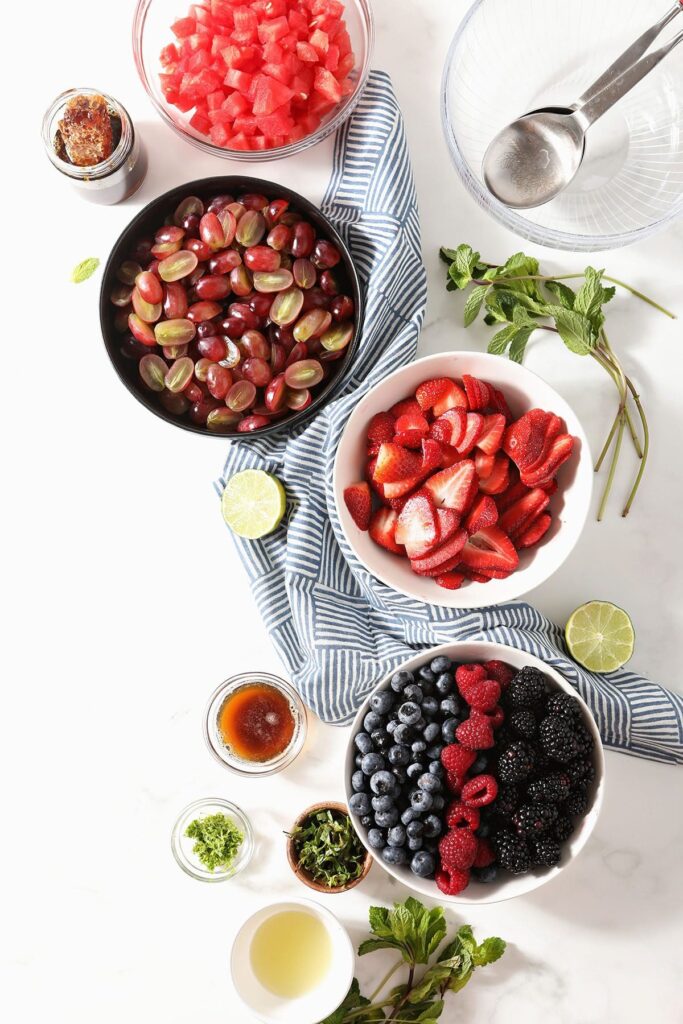 Bowls of fruit to make fruit salad on marble with a blue towel