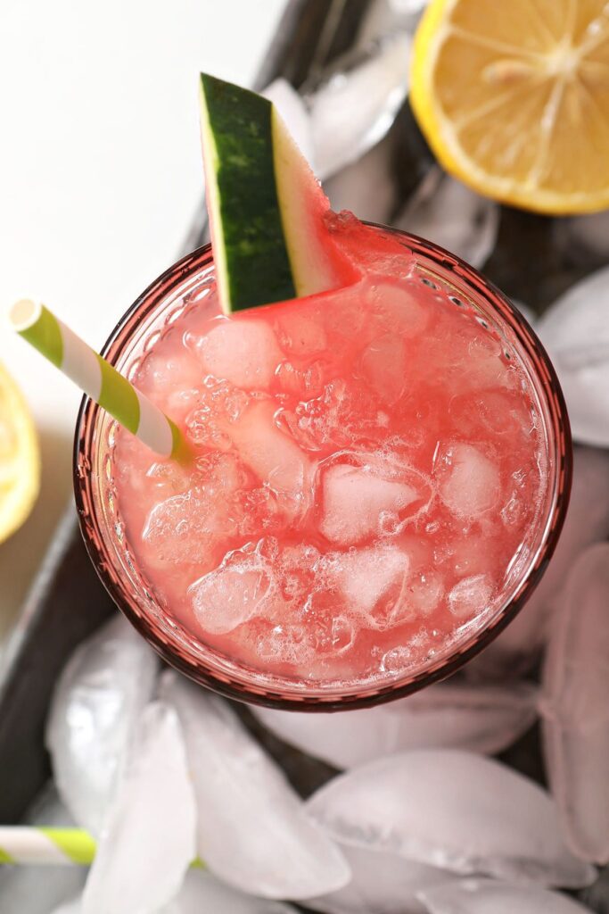 Close up of a glass of watermelon lemonade from above on an ice-covered tray