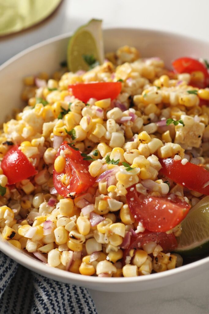 Close up of Charred Corn Salsa with tomatoes, limes and more in a white bowl