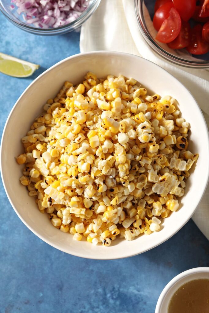 Charred corn in a bowl surrounded by other ingredients