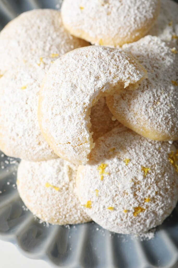 Close up of a bitten-into Lemon Cooler Cookie stacked on others