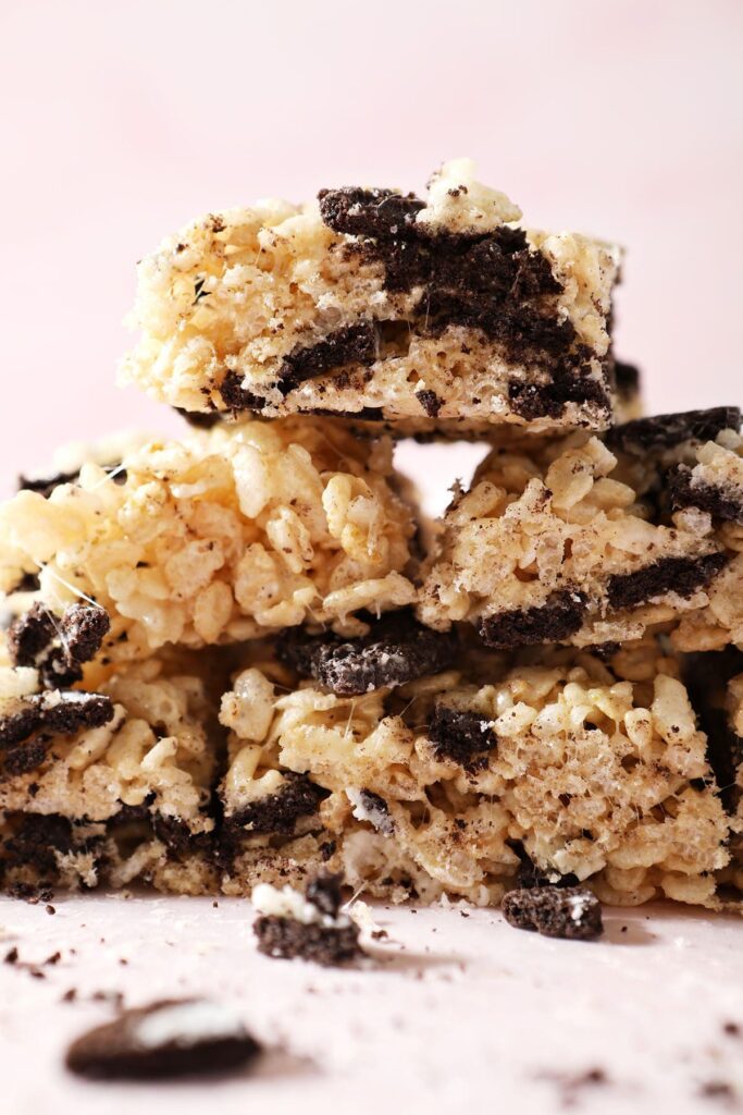 Cookies and cream Rice Krispie treats stacked on a pink countertop