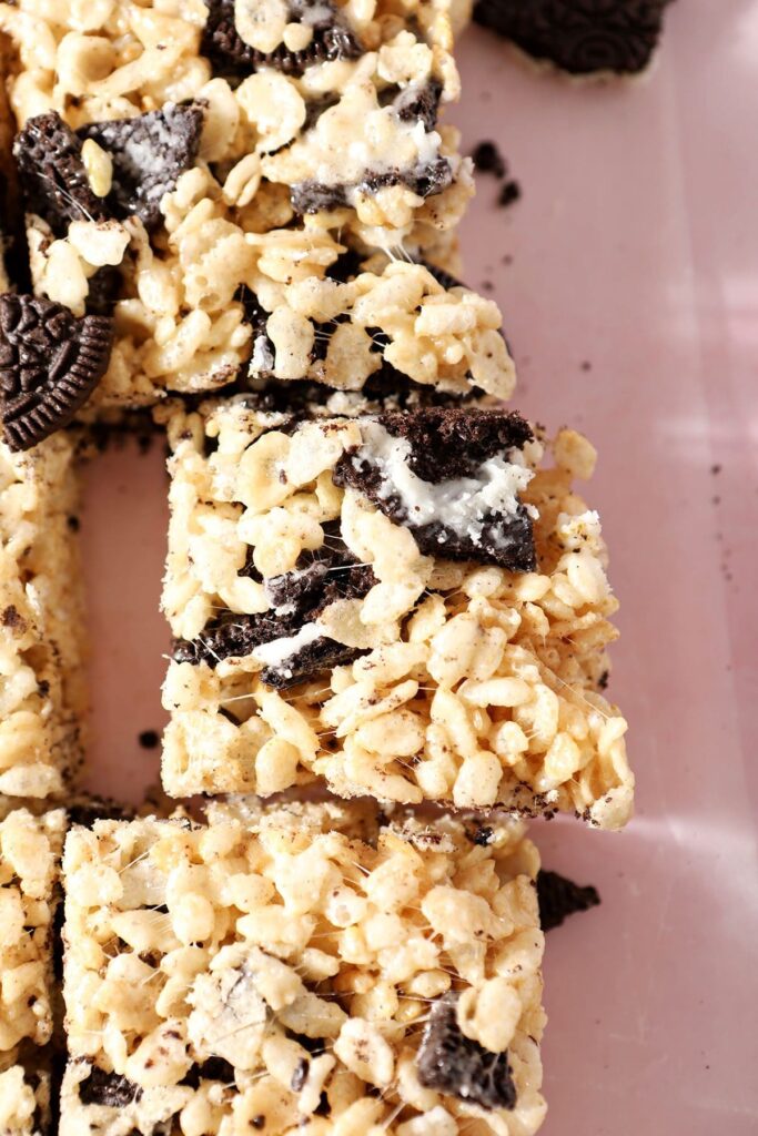 Three crispy rice treats with Oreos inside lined up on a pink counter