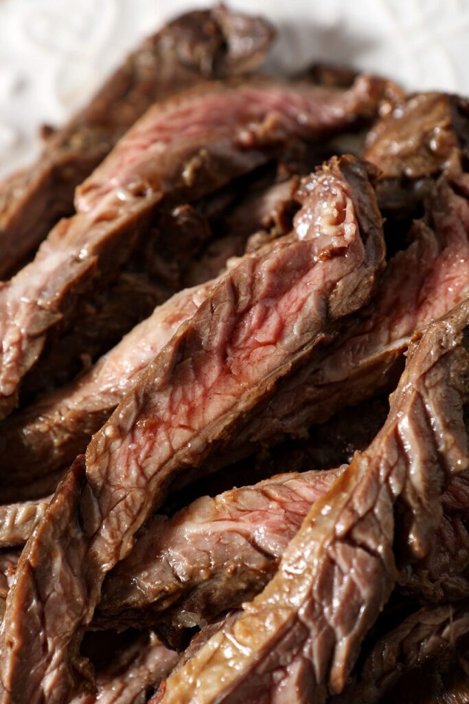 Close up of sliced skirt steak on a white plate