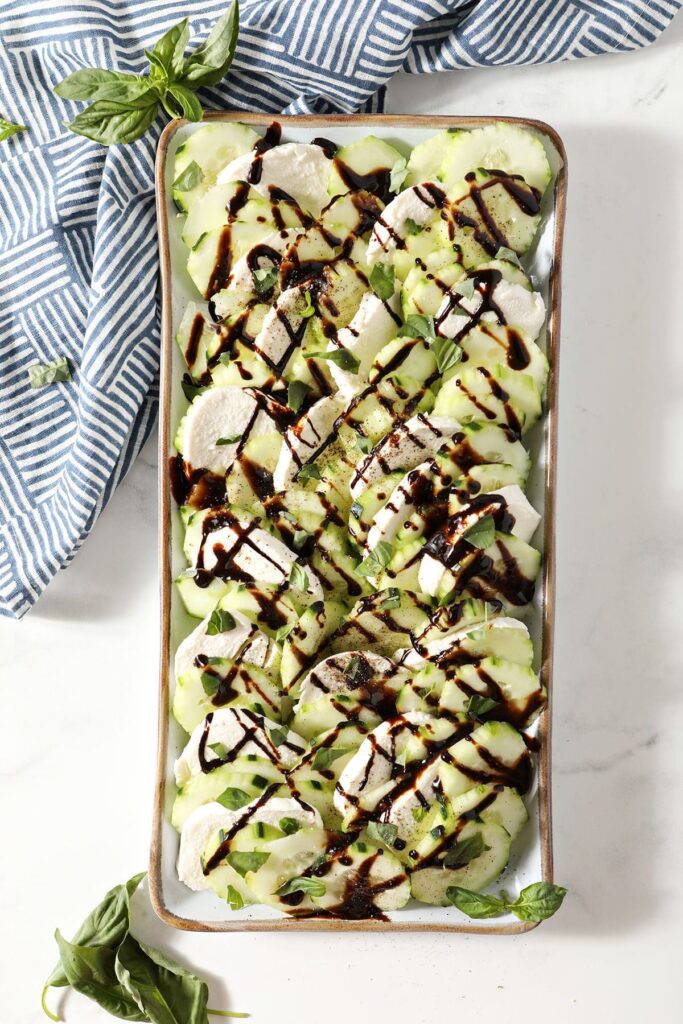 Cucumber Caprese Salad on a white platter on marble