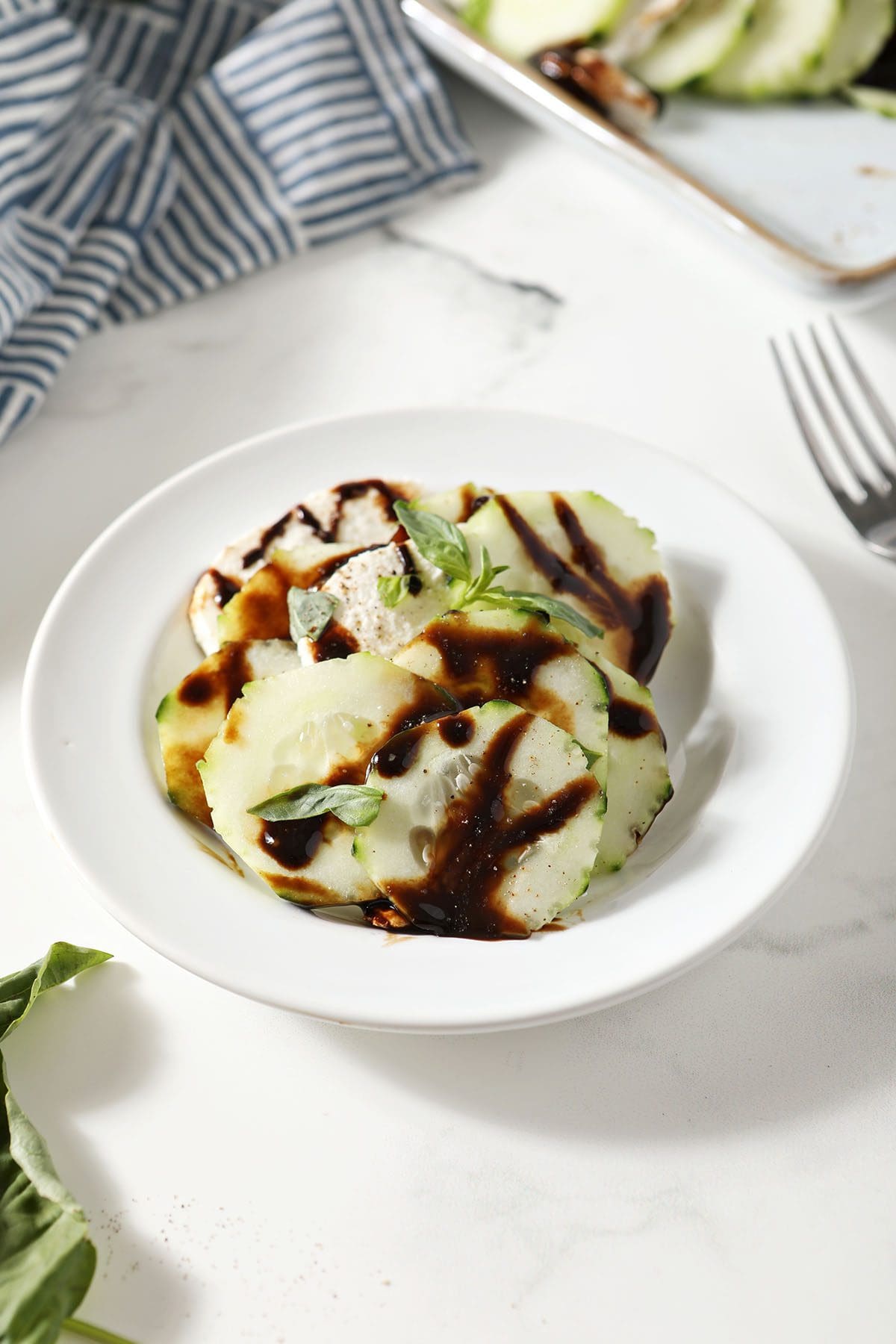 Cucumber caprese salad on a white plate on marble
