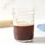A jar filled with brown butter on marble