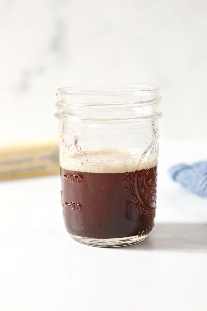 A jar filled with brown butter on marble