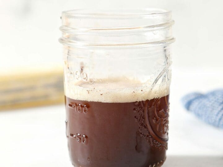 A jar filled with brown butter on marble